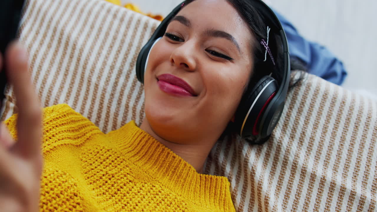 Woman listening to music with headphones on couch