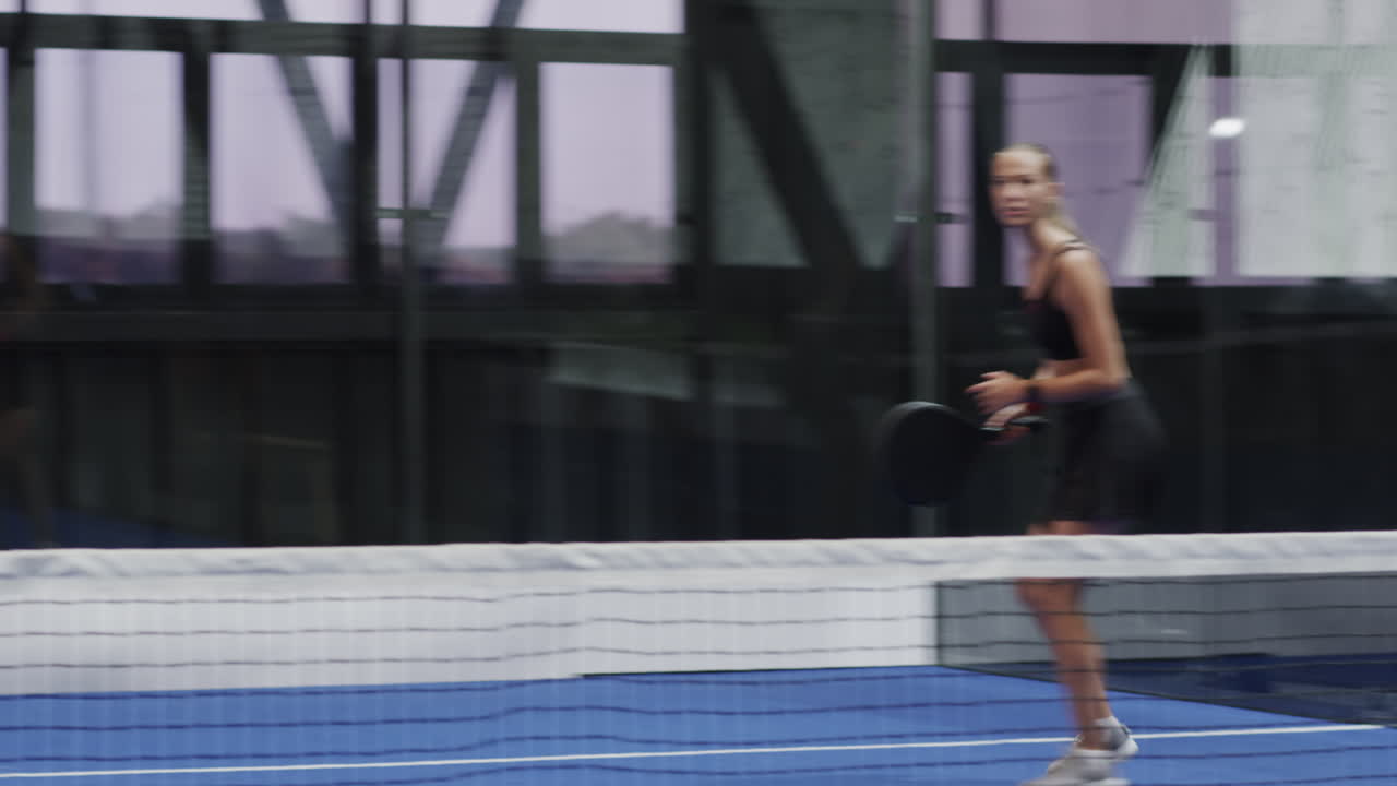 Diverse diverse players enjoying padel tennis match on indoor court, showing excitement