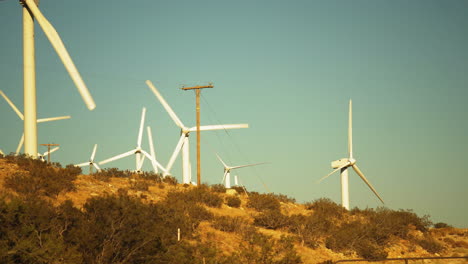 Lots-of-fast-rotating-wind-turbines-hillside-on-a-sunny-day-near-Palm-Springs-in-the-Mojave-Desert,-California,-USA