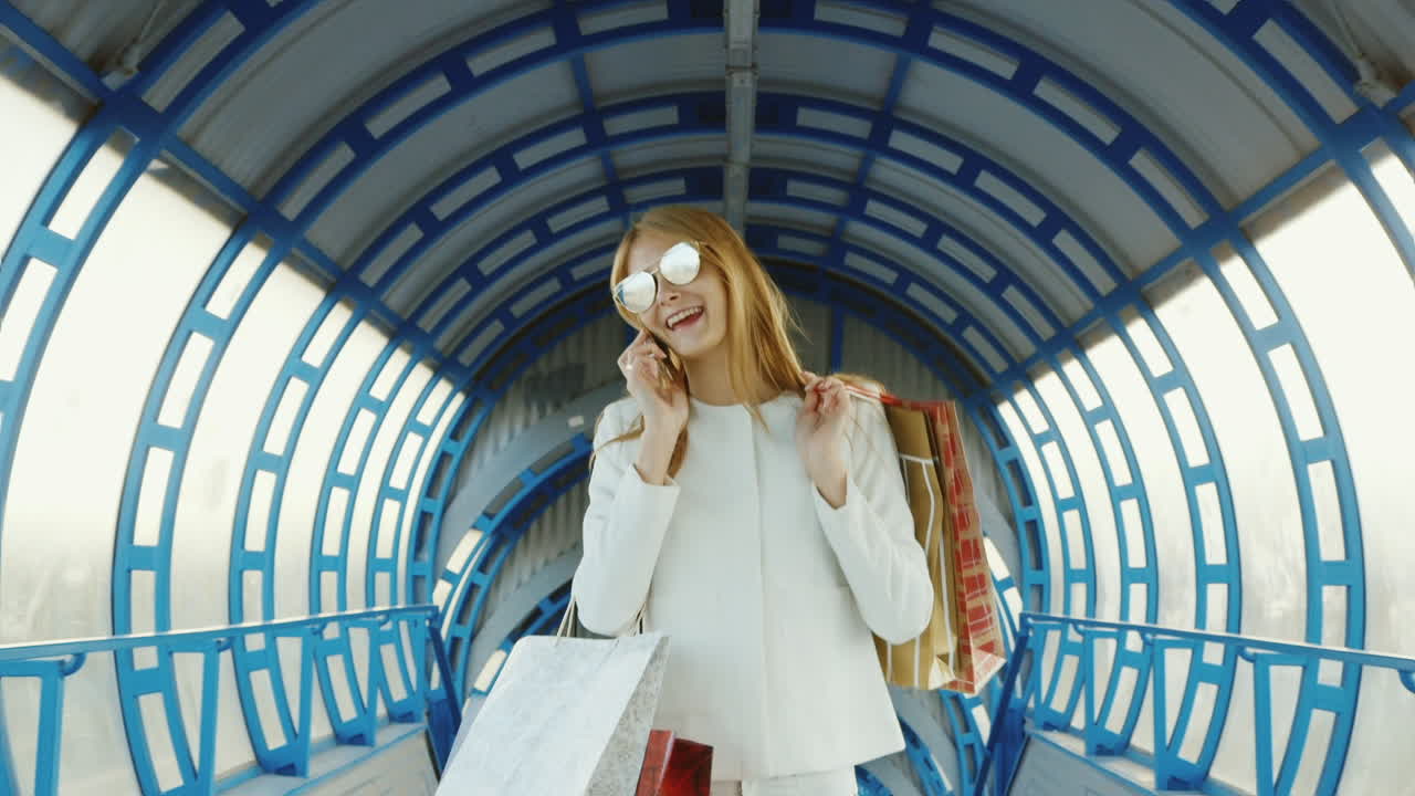 세련된 여성이 쇼핑백을 들고 전화로 성공적인 쇼핑 개념을 이야기합니다.