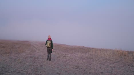 mujer caminando en las montañas brumosas al amanecer