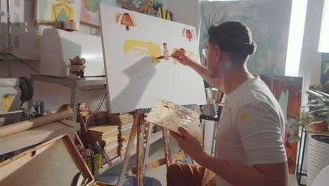 artist painting picture with palette knife in studio