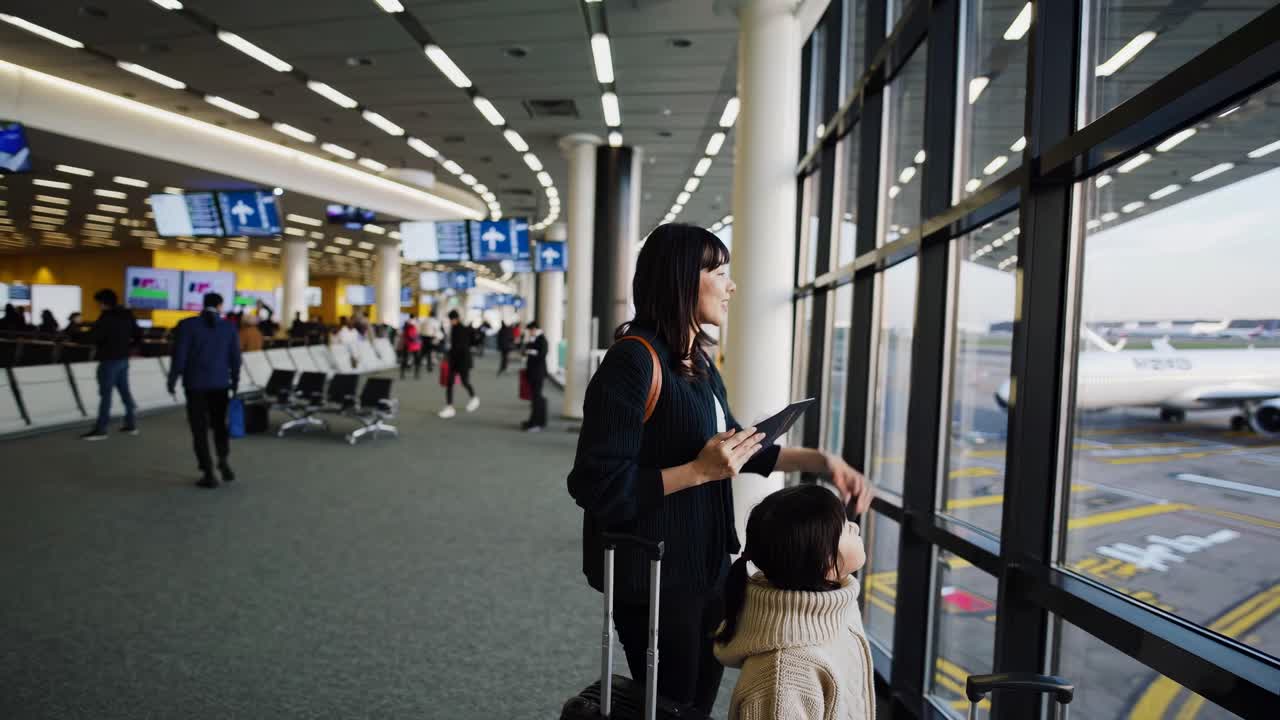 Wide-angle video shot of a woman and child at an airport window, capturing a candid travel moment