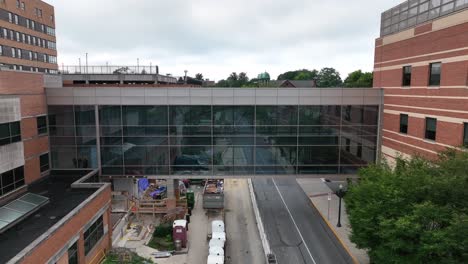 descending aerial footage reveals city sky bridge connecting two buildings