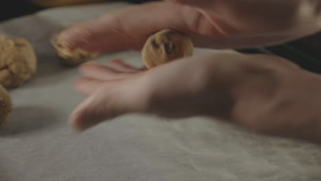 hands rolling cookie dough and placing on tray with baking sheet - close up