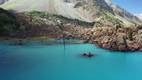 cinematic drone shot over the turquoise colored water in the mountains at naltar valley in pakistan, slowly revealing aerial shot