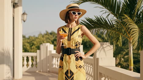 elegant woman in dress with cocktail on balcony