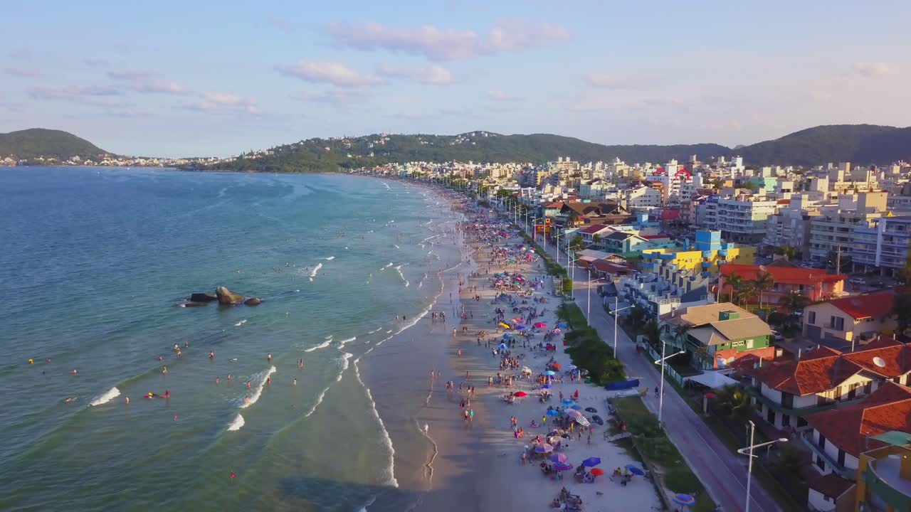 Inquadratura aerea panoramica della spiaggia di Bombas affollata di turisti che si godono l'ora d'oro.