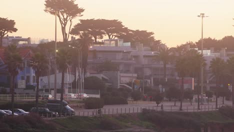 aerial, tracking, drone shot, overlooking the praia de sao pedro do estoril city, the portuguese coast and the sea, at sunset, on a sunny day, in cascais, portugal