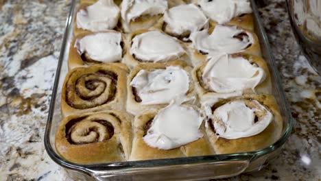 dabbing frosting or icing on freshly baked cinnamon rolls - isolated close up