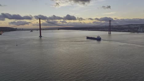 Drone-shot-of-tanker-ship-at-dusk-in-Lisbon,-descending-and-tilting-up