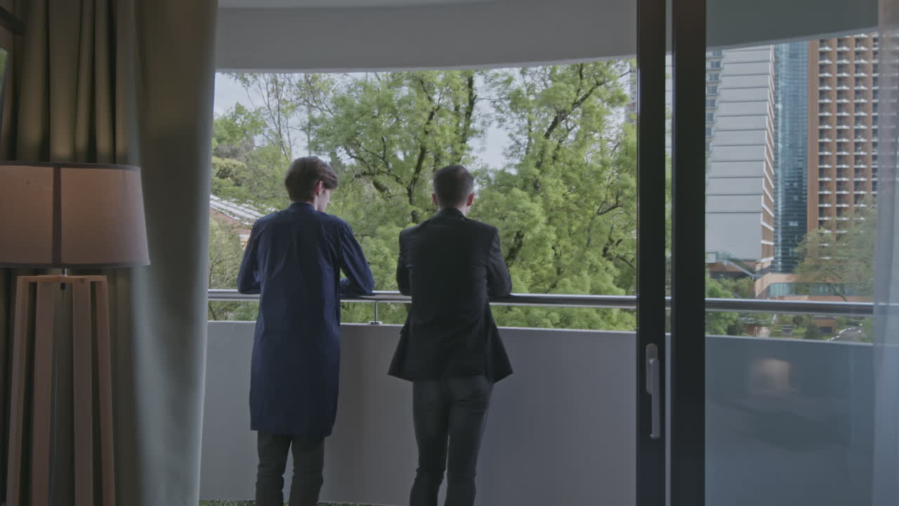 도시 전망 을 가진 발코니 에 있는 남자 들