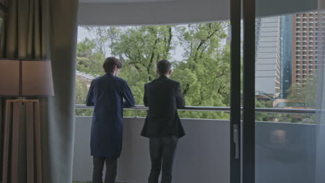 men on balcony with city view