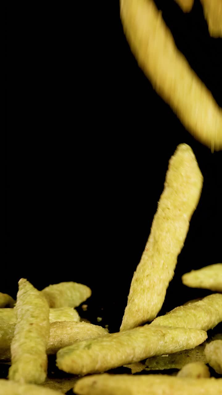 Green Snack Sticks Falling in Slow Motion on Black Background