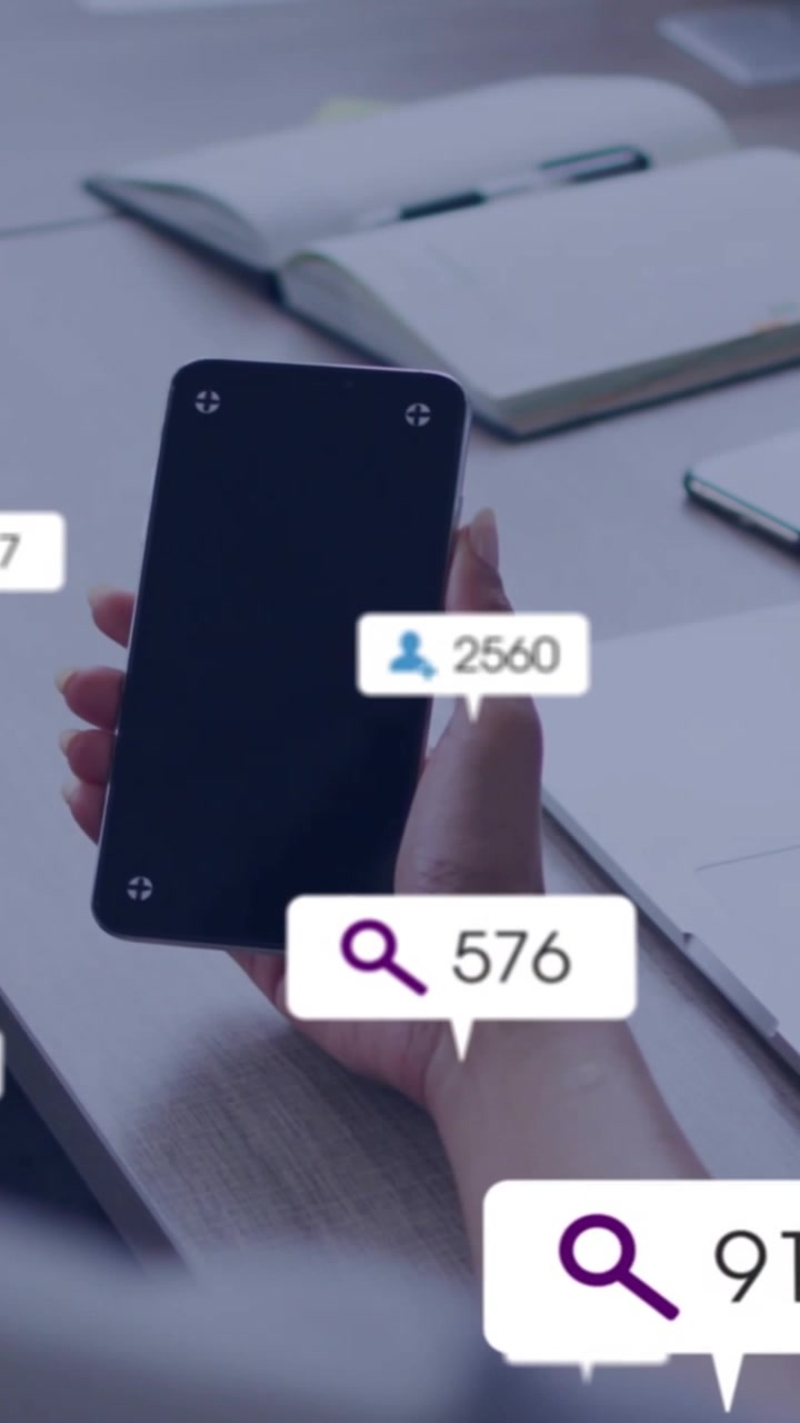 Vertical video: Woman holding phone on desk causing popping stats over phone fading for marketing