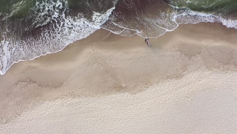 AERIAL:-Top-View-of-Married-Couple-Enjoying-Romantic-Walk-Alongside-Baltic-Sea