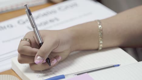 With-delicate-strokes,-woman's-hand-captures-thoughts-and-ideas-in-pages-of-notebook