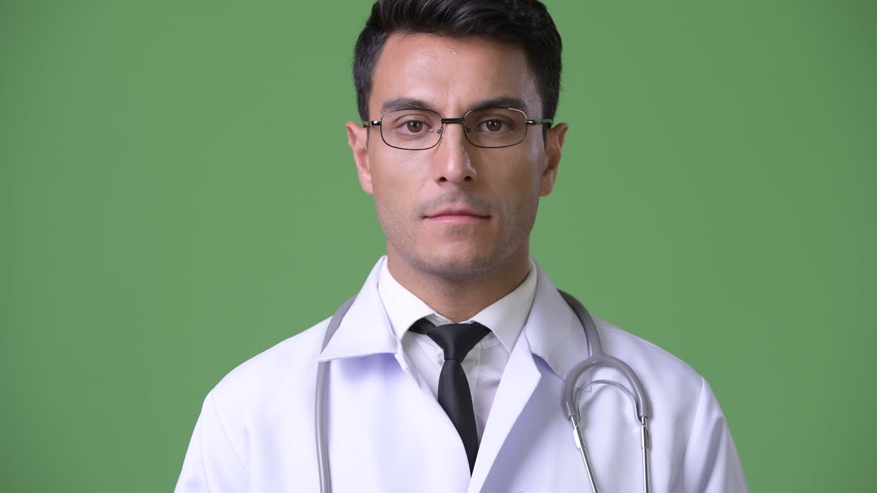 초록색 배경에 젊은 잘생긴 히스패닉 남자 의사