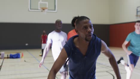 Diverse-male-basketball-players-in-action-during-game-at-indoor-court,-slow-motion