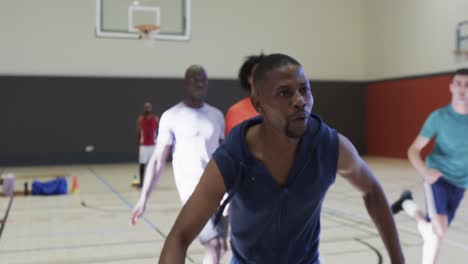 diverse male basketball players in action during game at indoor court, slow motion