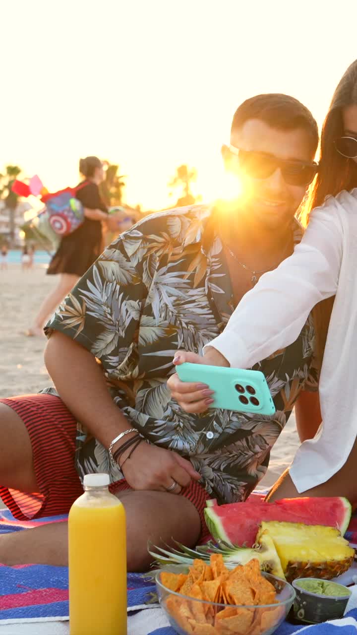 Amici che si godono un picnic in spiaggia e si scattano un selfie
