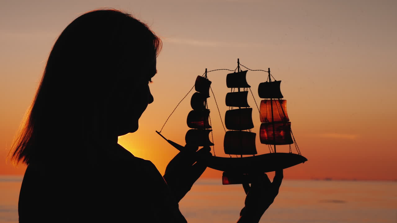 석양에 장난감 범선을 가진 여자의 프로필