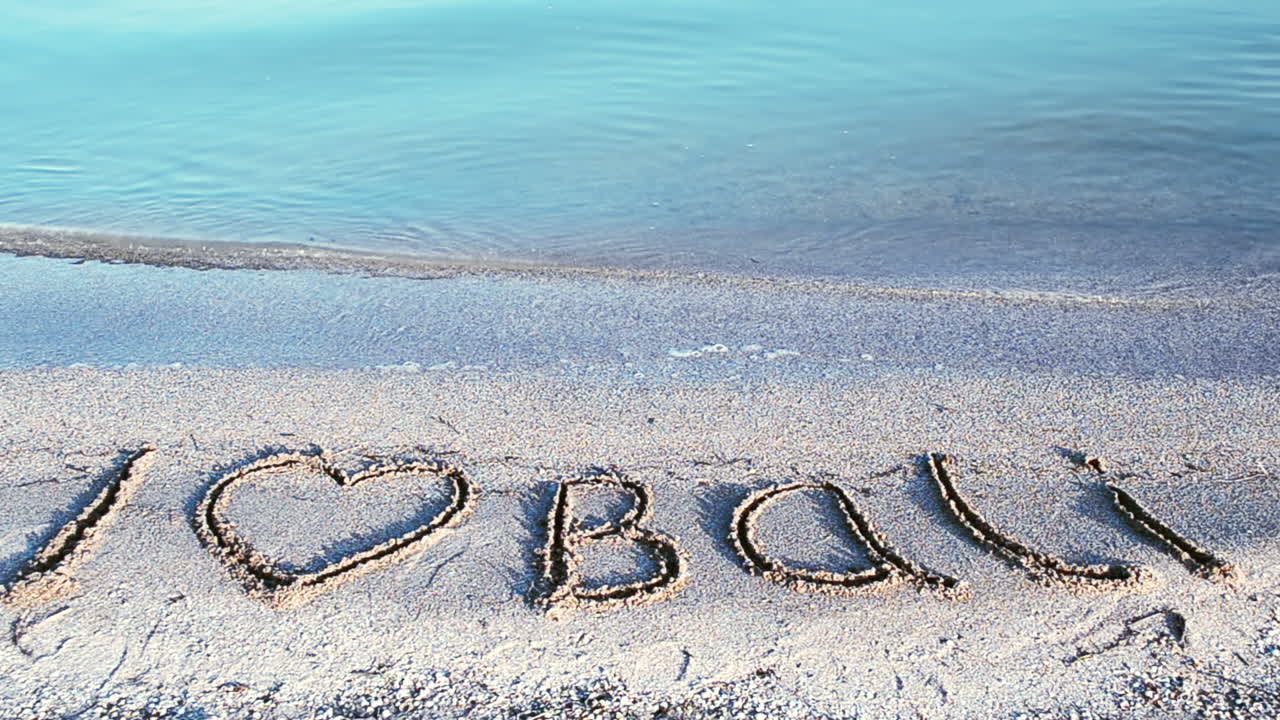 Inscription Bali on sandy beach. Inscription on sand, the beach