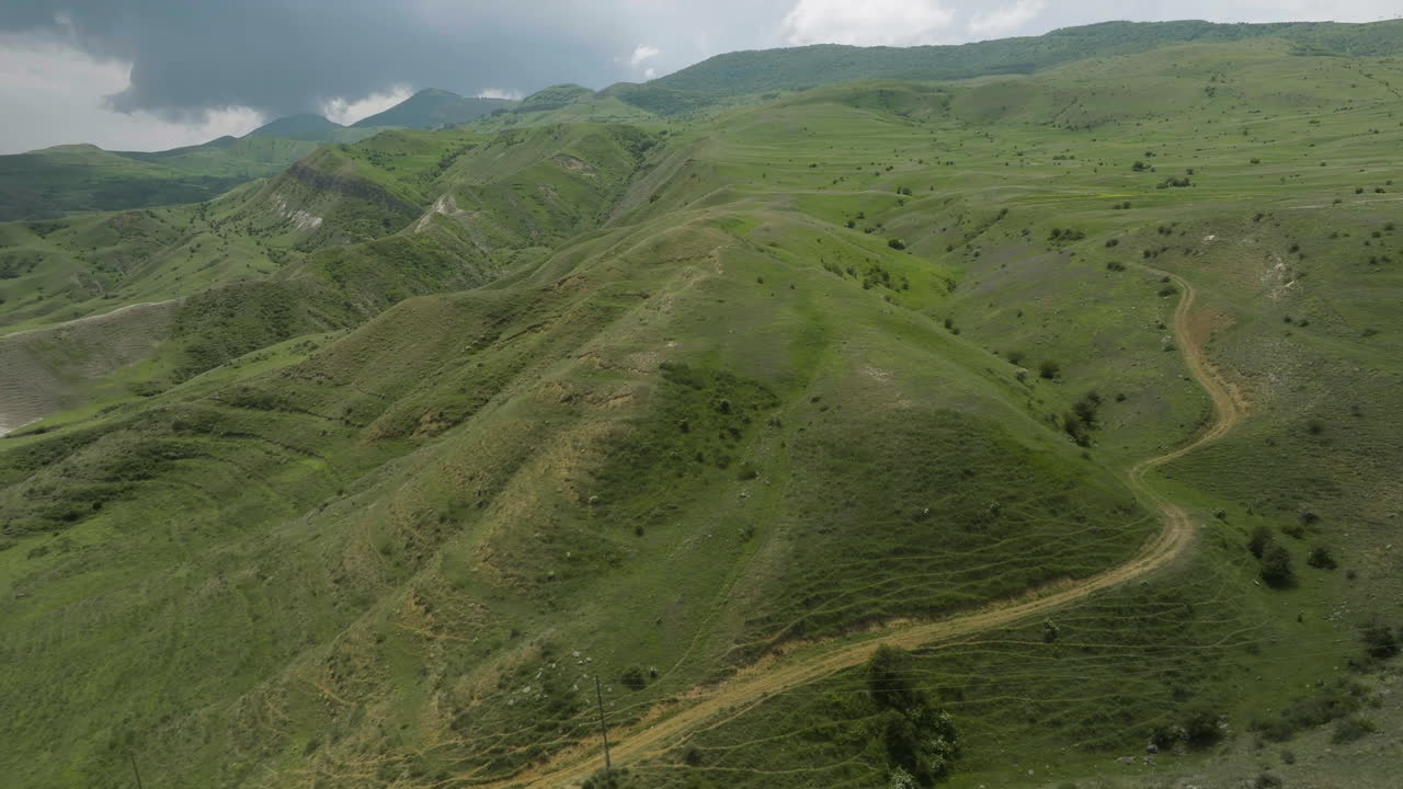 Sentiero escursionistico tortuoso attraverso verdi catene montuose alla luce del giorno in Georgia