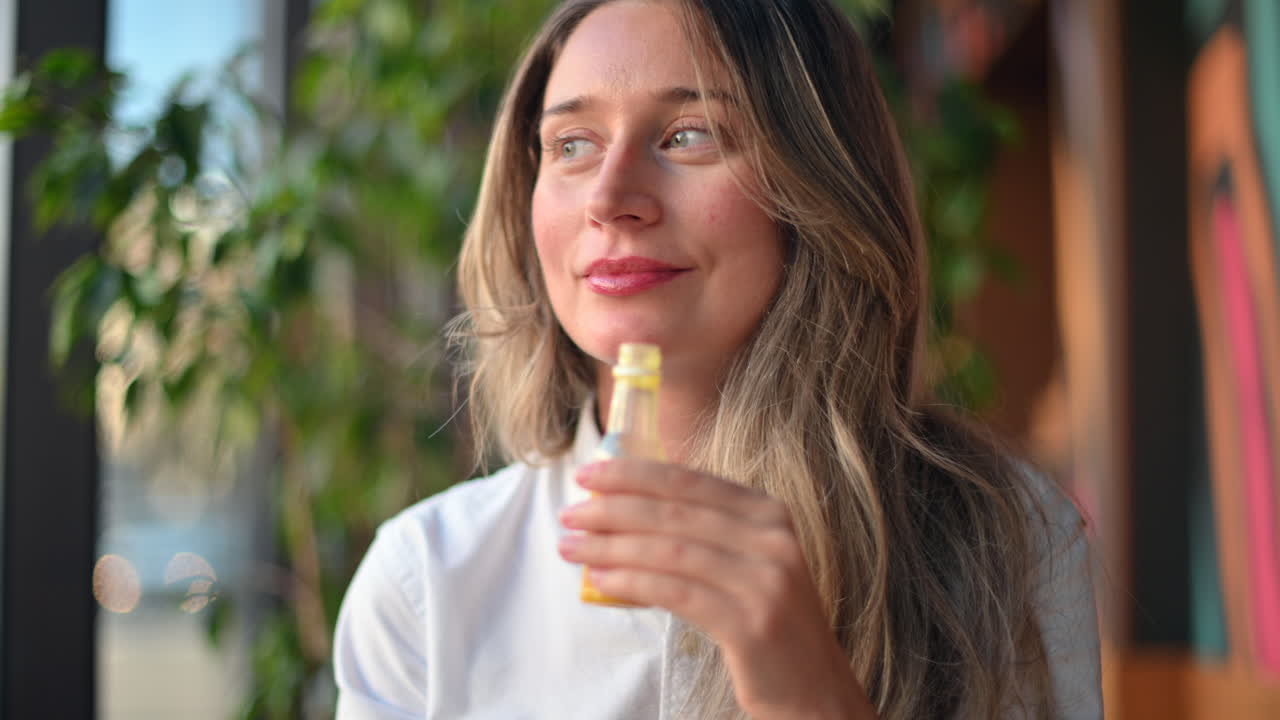 Happy woman drinking fresh ginger juice from a small plastic bottle