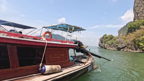 traditional boat navigating past towering limestone cliffs