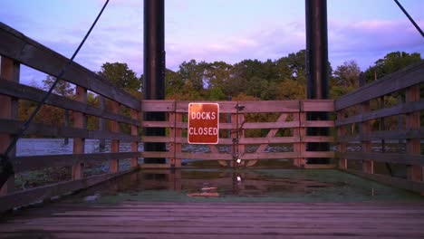 Wide shot of Docks Closed sign at a closed boating docks gate during sunset