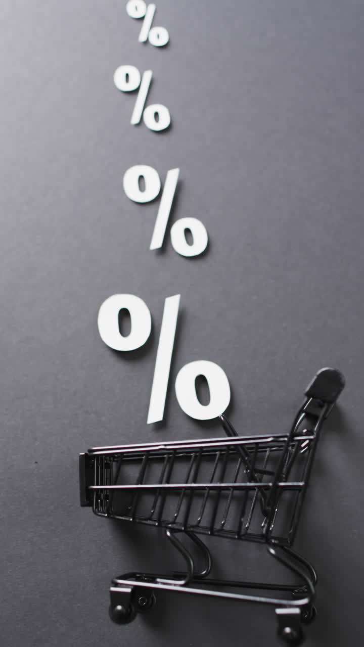 Vertical video of shopping trolley and white percent signs on grey background