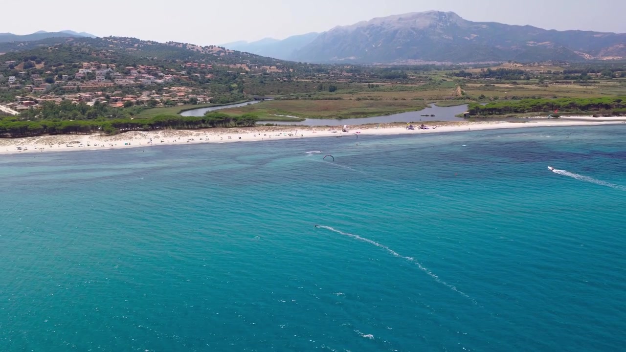 İtalya, Sardinya'daki La Caletta'da, bir kitesurfçü havada tahtadan kısa süreliğine ayrılarak yeniden bağlanmadan önce board-off tarzı bir numara yapıyor