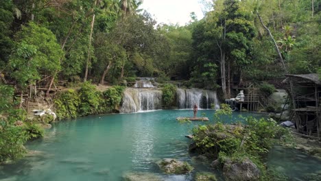 blond female influencer with great body standing on bamboo raft at cambugahay falls