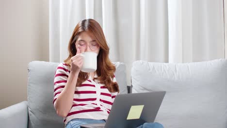 노트북을 사용하여 친구와 채팅하는 동안 차 한 잔을 즐기는 젊은 여성