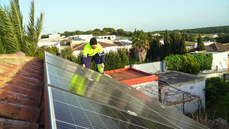 un experto instalando paneles solares sobre un techo de ladrillo en el pueblo en un día soleado con viento