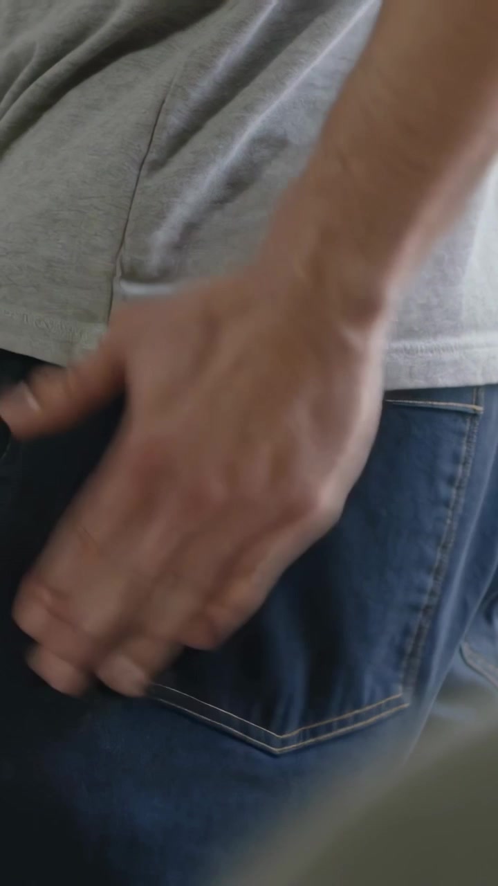 Vertical video: Entering right hand brushing jeans pocket in interior, removing lint from seam