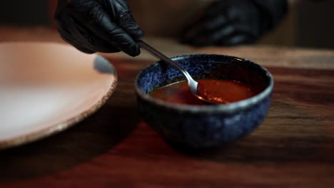 Chef-with-gloves-preparing-pasta-plate-with-tomato-sauce