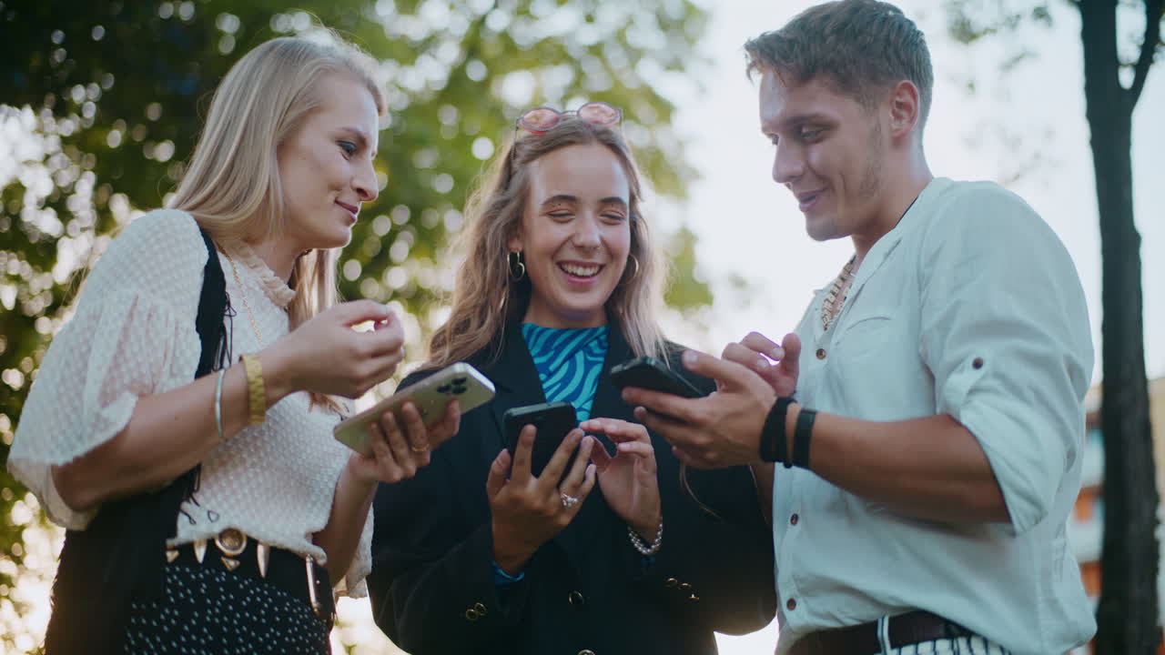 amigos compartiendo teléfonos inteligentes al aire libre