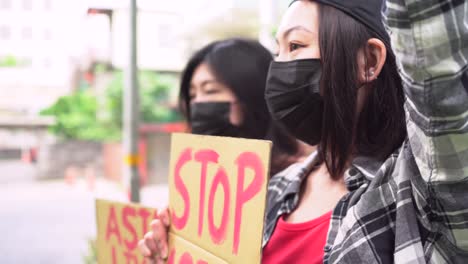 asian women with posters during protest in city