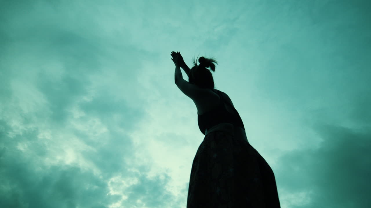 Woman in Yoga Pose Against a Dramatic Sky