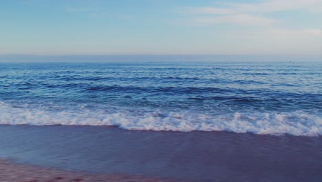 Drone-Volando-En-Círculo-En-La-Playa-Cerca-Del-Mar-Y-Durante-La-Puesta-De-Sol