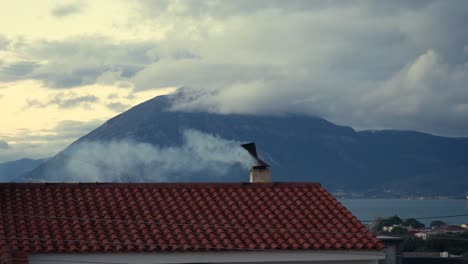 humo saliendo de una tapa giratoria de chimenea de un techo de tejas en un frío día de invierno