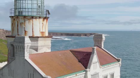 historic lighthouse on california coastal cliffs, aerial close orbit