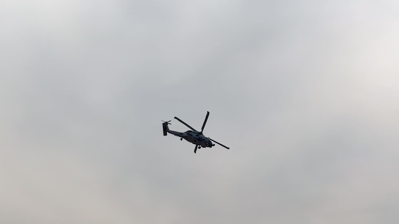 Sikorsky Seahawk performs aerial maneuvers against cloudy skies at Avalon Airshow, Geelong, Australia. Spectators watch the dynamic display
