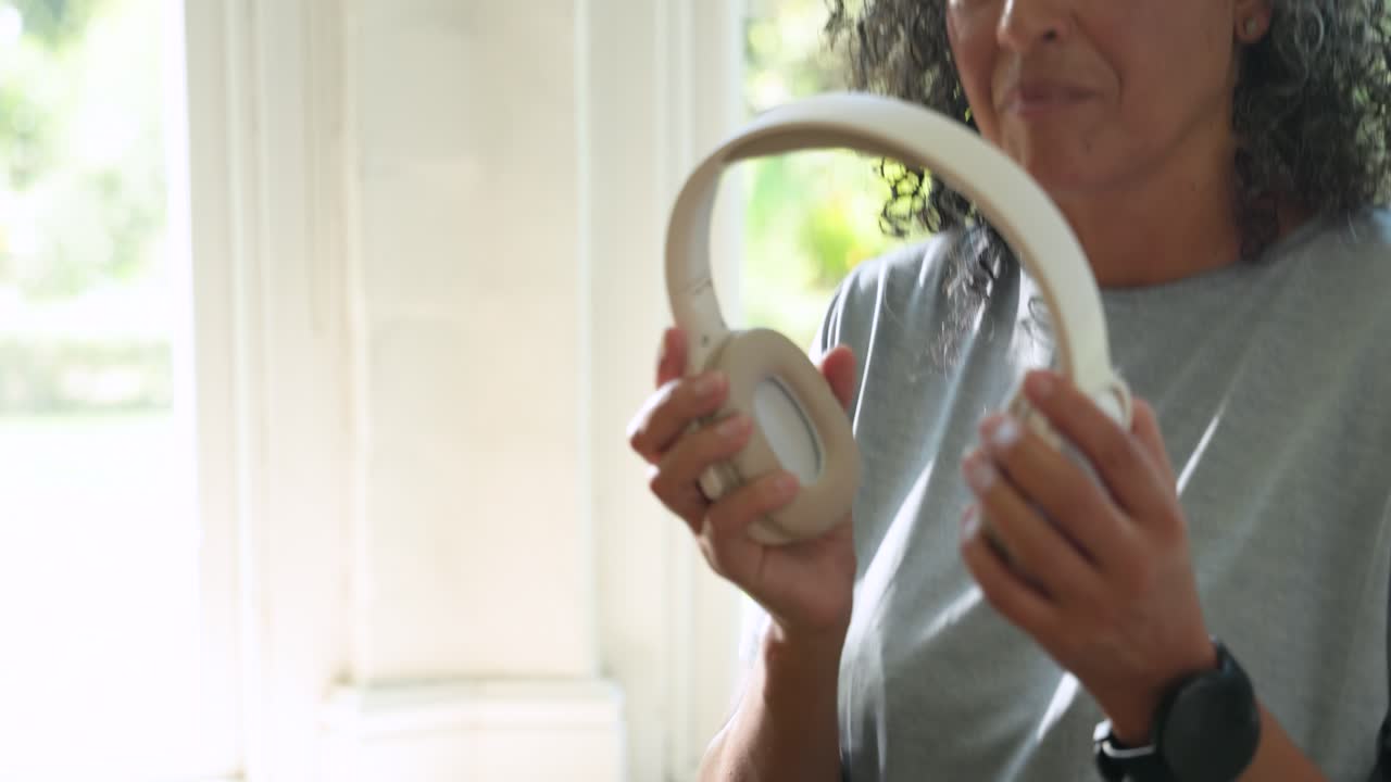 Video verticale: Donna afroamericana che tocca il telefono, prende una bottiglia, indossa le cuffie e ascolta su un tappetino.