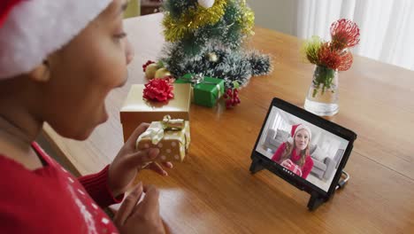 Mujer-Afroamericana-Con-Sombrero-De-Santa-Usando-Tableta-Para-Videollamada-Navideña-Con-Mujer-En-Pantalla