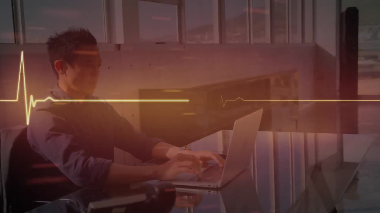 animación de un monitor cardíaco contra un hombre de negocios asiático que usa una computadora portátil en la oficina