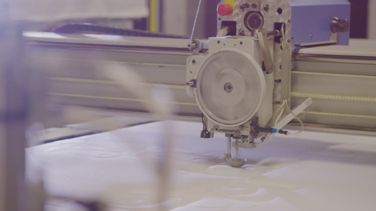 Linha de produção industrial de camas box com máquinas em movimento.