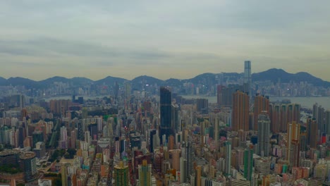 Drone-shot-,traveling-to-the-right-and-forward,-of-a-big-city-during-a-cloudy-day-with-business-buildings-in-the-distance